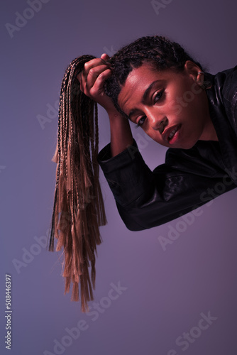 Stylish african aerican woman holding pigtails and looking at camera isolated on purple. photo