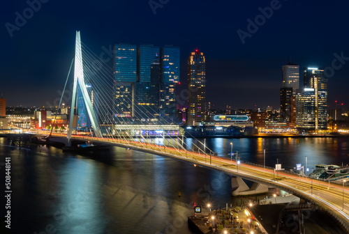 Rotterdam nighttime panorama with “Erasmus-Bridge“ over river Nieuwe Maas at evening blue hour in South Holland Netherlands. Waterfront with illuminated bridge and tall buildings on the waterfront.