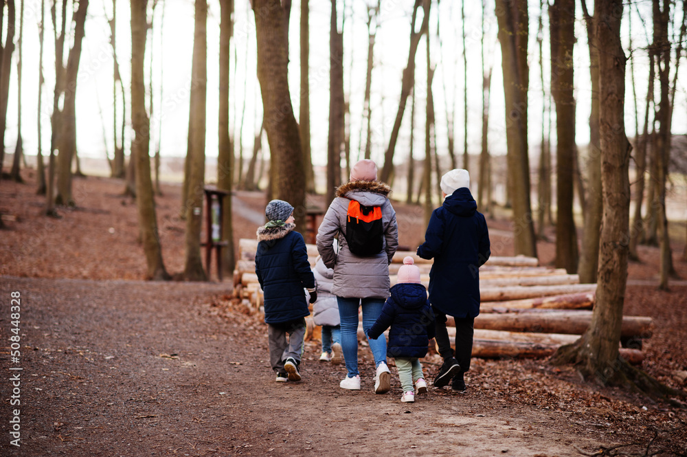 Back of mother with four kids wear jacket and hat in early spring forest. Back of mother with four kids wear jacket and hat in early spring forest.