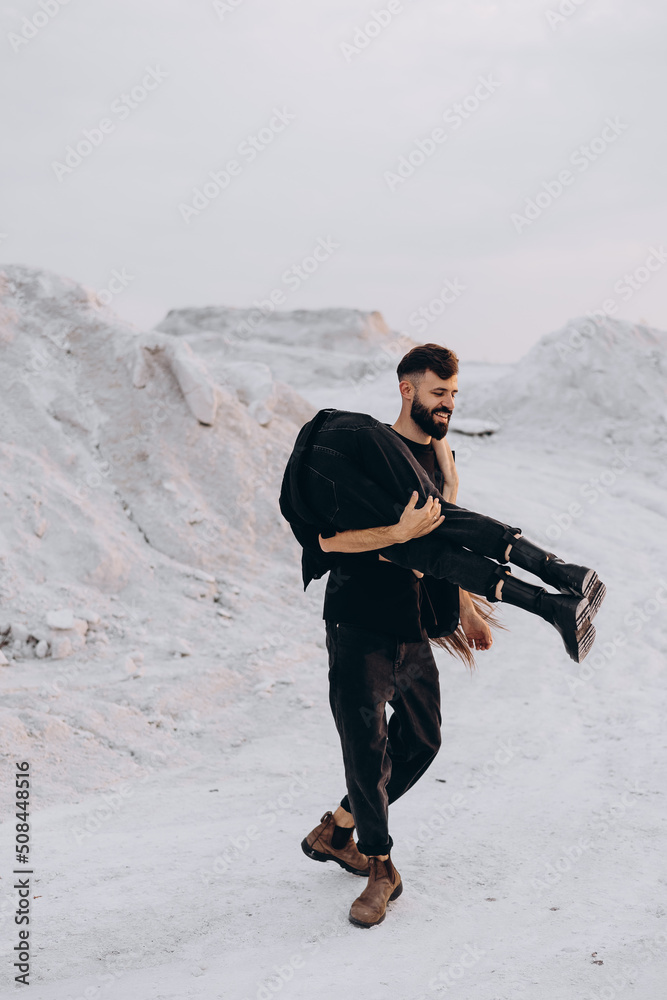 Stylish couple walking and hugging walking on a background of white mountains. Lovely hipster couple enjoying time together. The concept of youth, love and lifestyle. Springtime.