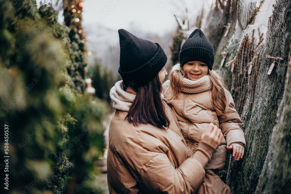 Φωτογραφία Winter holidays and people concept - happy family with little daughter choosing Xmas tree at Christmas tree fair