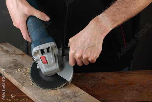 Photo the person holds an angle grinder in his hands