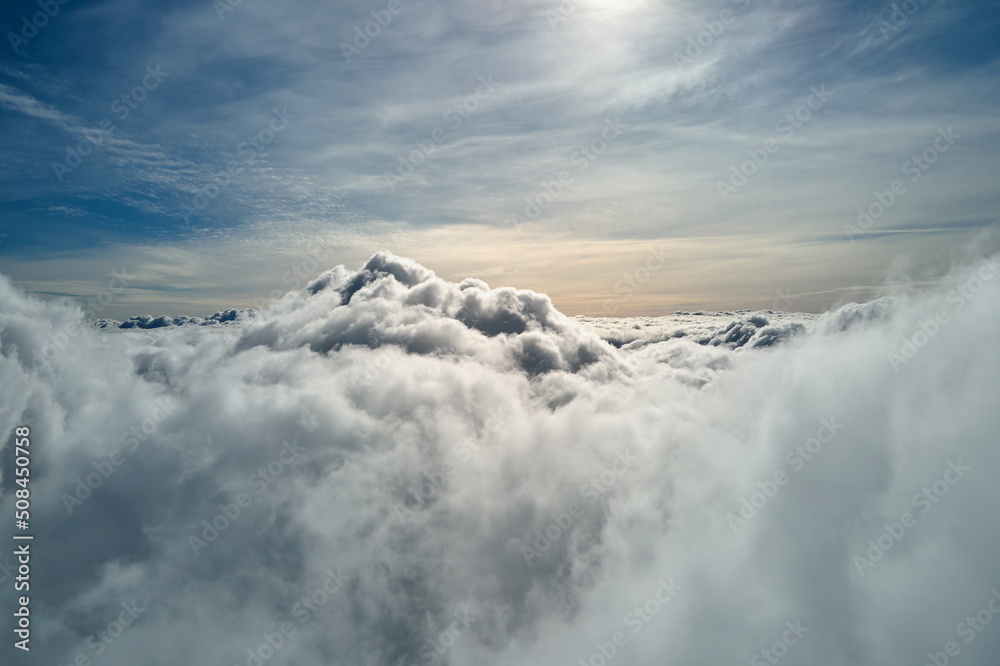 Aerial view from airplane window at high altitude of earth covered with white puffy cumulus clouds