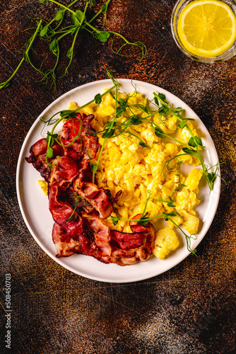 Traditional breakfast scrambled eggs with fried bacon