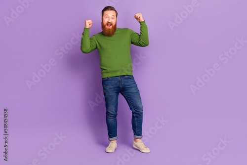Full body photo of satisfied delighted man raise fists celebrate accomplishment isolated on violet color background © deagreez