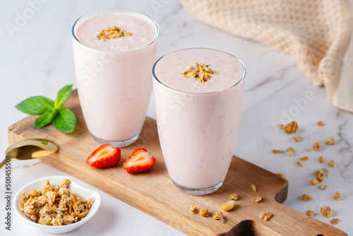 Yogurt , buttermilk or kefir with granola and strawberry. Yogurt in glass on light background. Probiotic cold fermented dairy drink. Gut health, fermented products, healthy gut flora concept. photo