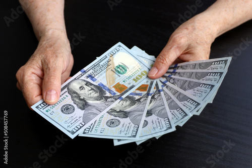 US dollars in wrinkled hands of elderly woman. Concept of pension payments, savings at retirement, pensioner with money