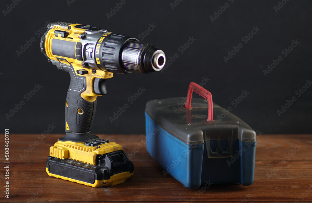 yellow screwdriver with a box of drill bits on the table yellow screwdriver with a box of drill bits on the table