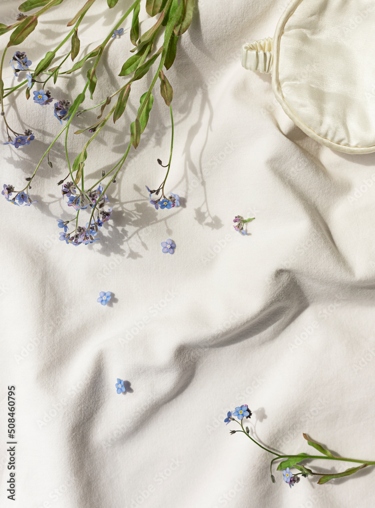 White organic cotton blanket with forget me not flowers and sleeping mask. Copy space White organic cotton blanket with forget me not flowers and sleeping mask. Copy space