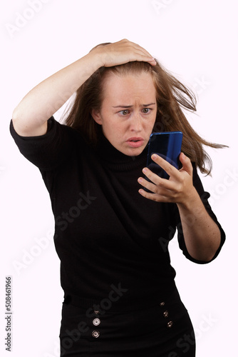 Chica joven con cara de preocupada leyendo un mensaje en su teléfono