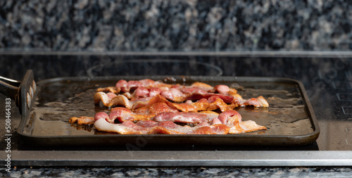 Bacon frying on the stove top with a shallow depth of field and copy space