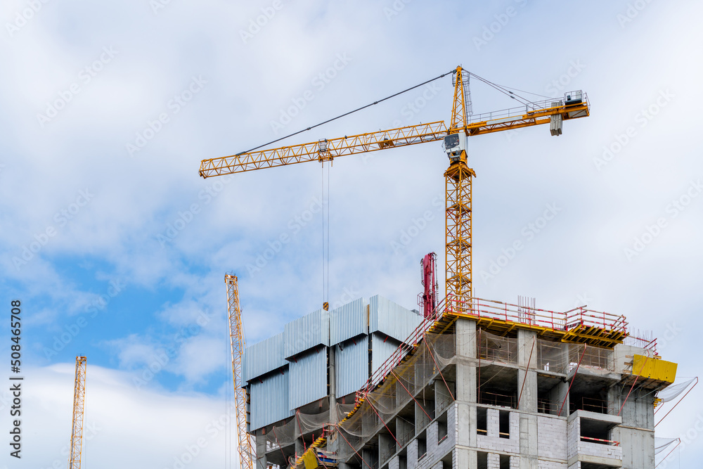 Construction cranes near the facade of a house under construction. modern building industry. Sale and rental of real estate.