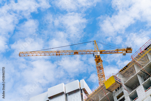 Construction cranes near the facade of a house under construction. modern building industry. Sale and rental of real estate.
