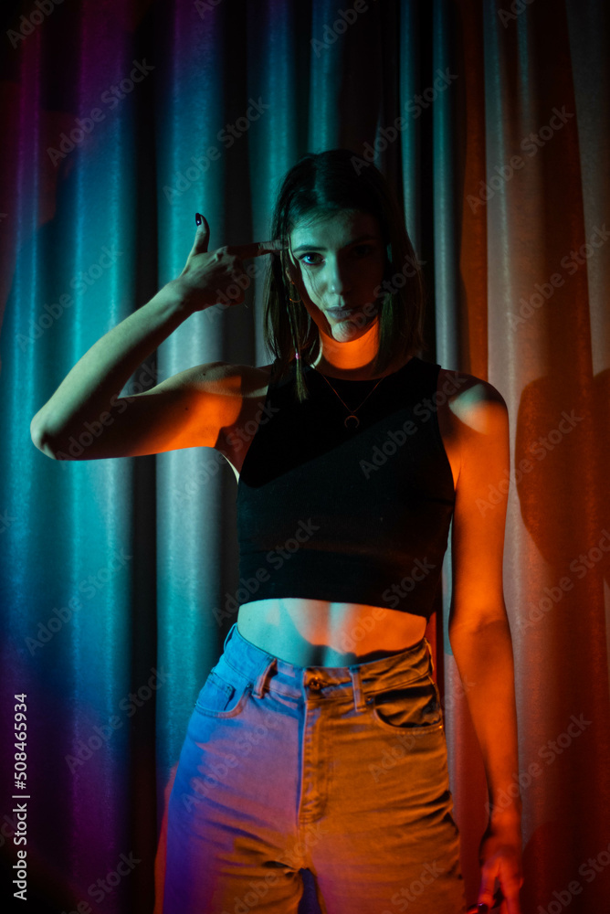 Young and sexy woman with wearing jeans and black t-shirt posing in colorful neon light Young and sexy woman with wearing jeans and black t-shirt posing in colorful neon light