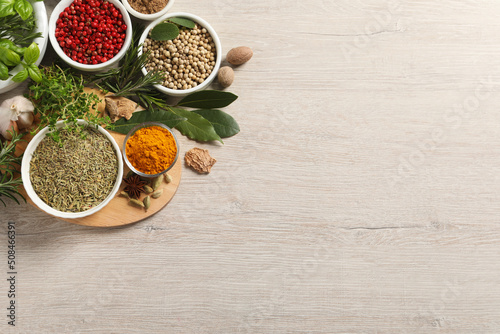 Different herbs and spices on wooden table, flat lay. Space for text