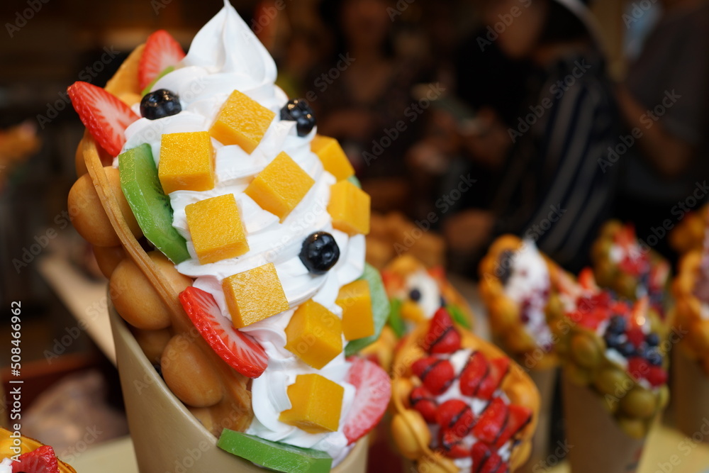 Dummy set of famous Hong Kong egg waffle with strawberry, berries, kiwi, mango and cream pouring honey on top. 