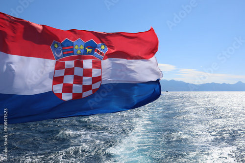 Flag of Croatia against the background of the sea, sea coast and blue sky