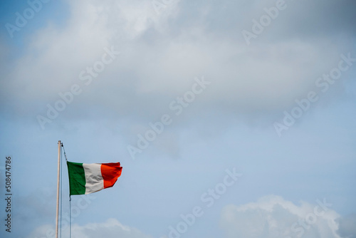National flag of Ireland waving in a wind. Cloudy sky background. Copy space. Irish tricolor.