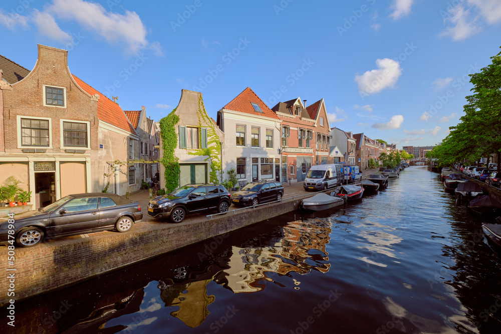 HAARLEM, NETHERLANDS - MAY 24, 2022: Clear reflections of canal-side houses on the Burgwal canal on a sunny evening.