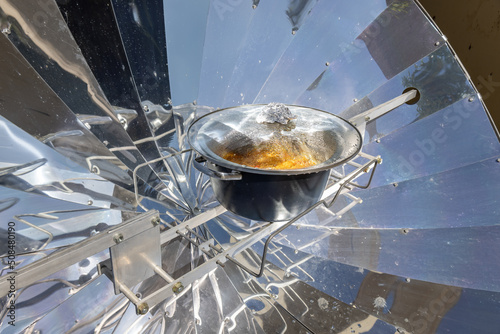 Cooking with sun energy, parabolic solar oven in the middle of cooking a dish thanks to solar energy photo
