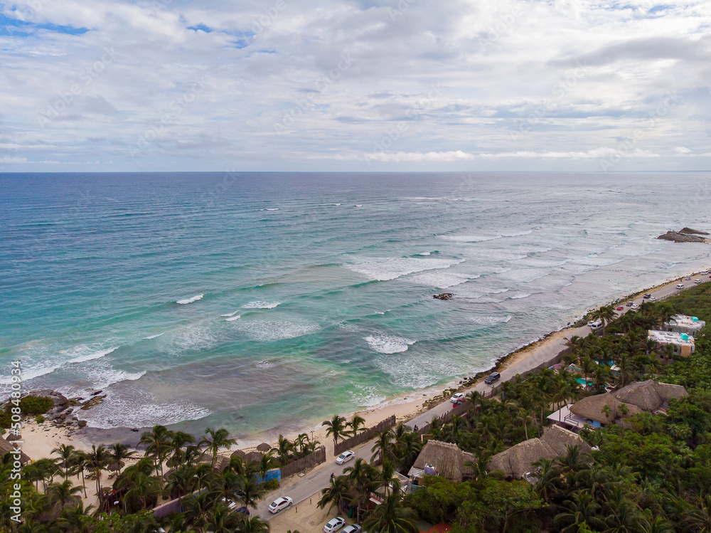 Aerial drone view of Tulum beach road surrounded by nature with wavy Caribbean Sea and white sand beach on a cloudy day Aerial drone view of Tulum beach road surrounded by nature with wavy Caribbean Sea and white sand beach on a cloudy day