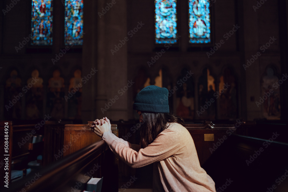 Young woman prayer's pray alone in church, People pray to God with folded hands, old wooden classic long chairs background