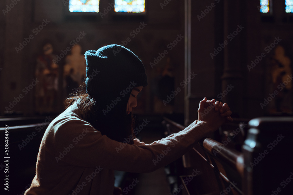 Young woman prayer's pray alone in church, People pray to God with folded hands, old wooden classic long chairs background