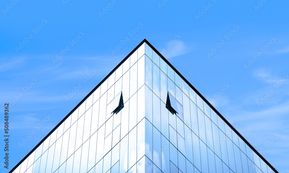 Manipulation techniques image of light reflection on surface of modern glass office building against blue sky in symmetry and low angle view Manipulation techniques image of light reflection on surface of modern glass office building against blue sky in symmetry and low angle view