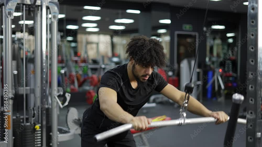 Young man exercising on lateral pull at gym for the back mucles, slow motion Young man exercising on lateral pull at gym for the back mucles, slow motion