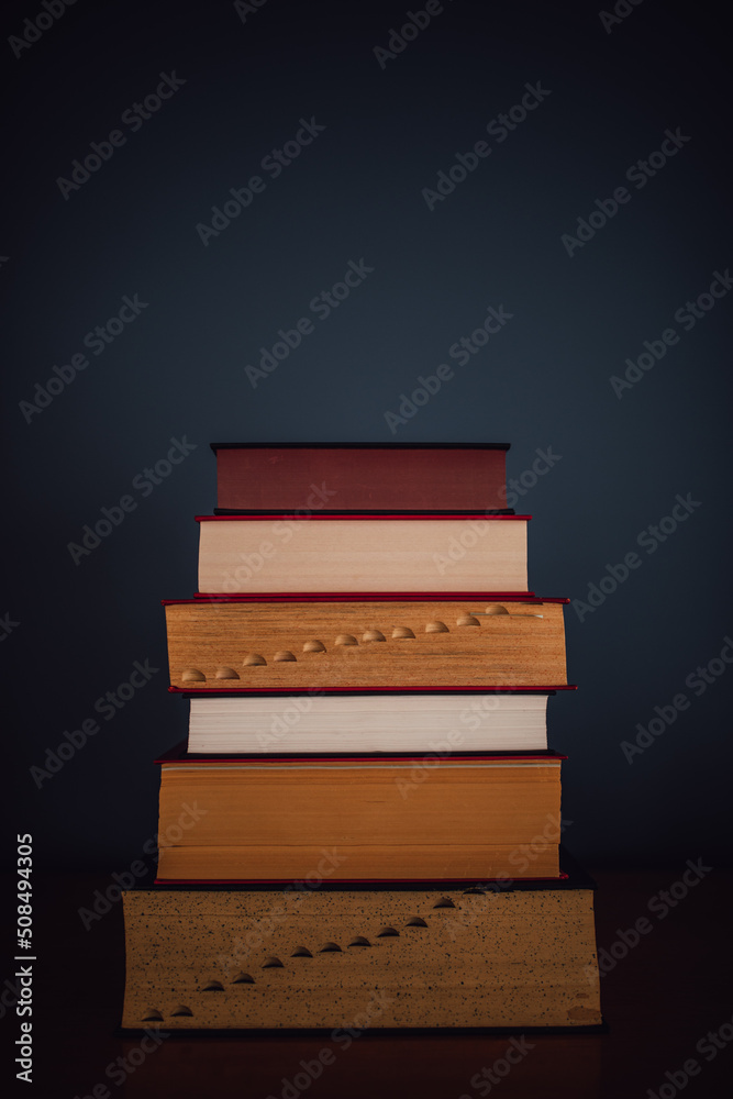 tall stack of five books against dark blue. copy space. tall stack of five books against dark blue. copy space.