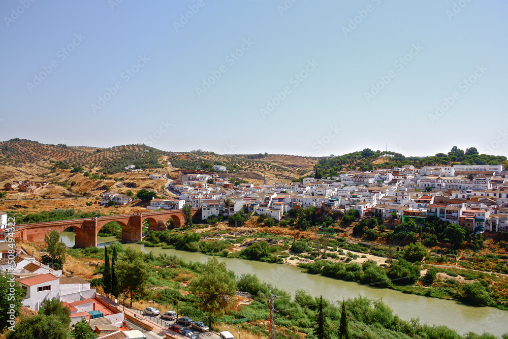 Wide view of Montoro, Andalusia, Spain, with its traditional white houses, the medieval bridge over the Guadalquivir river and the plantations in the background