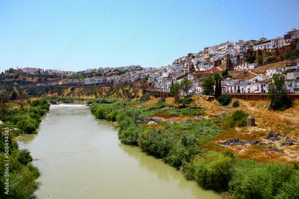 Guadalquivir river flowing at the foot of the hillside next to Montoro, Andalusia, Spain, on a sunny summer day
