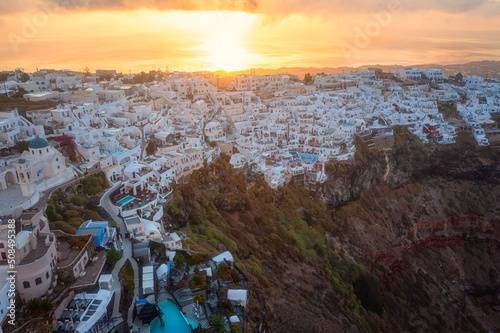 Santorini, Imerovigli village on the cliff with caldera view at sunrise, scenic aerial landscape with white architecture, Aegean Sea, colored sky with clouds and sun, outdoor travel background, Greece photo