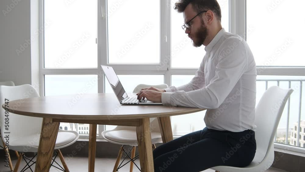 bearded male freelancer work in laptop at home in coworking kitchen. bearded male freelancer work in laptop at home in coworking kitchen.