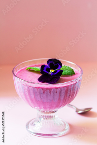 Obraz na płótnie Blackcurrant berry mousse garnished with viola flower and lemon balm leaf. w salonie
