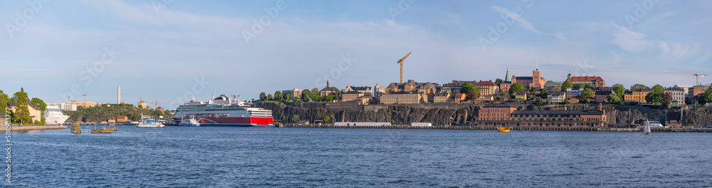 Panorama view over the bay Stockholms Ström in evening light with the district Södermalm and cruise ships and island with a castle and brick building a sunny evening in Stockholm Panorama view over the bay Stockholms Ström in evening light with the district Södermalm and cruise ships and island with a castle and brick building a sunny evening in Stockholm