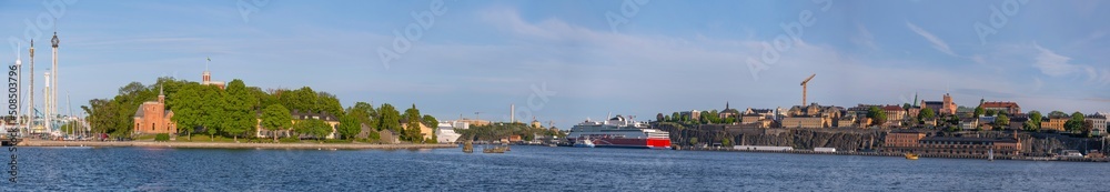 Panorama view over the bay Stockholms Ström in evening light with the district Södermalm and cruise ships and island with a castle and brick building  a sunny evening in Stockholm