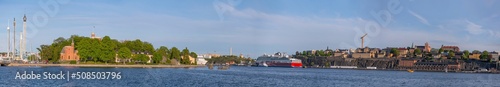 Panorama view over the bay Stockholms Ström in evening light with the district Södermalm and cruise ships and island with a castle and brick building  a sunny evening in Stockholm © Hans Baath