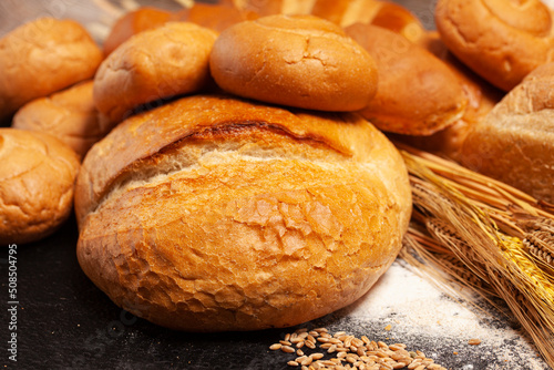 Culinary background with bread,sweet bun,wheat ears,grains on a black background.