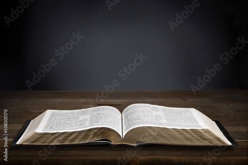 Fototapete Open Christian bible book on old wooden table.