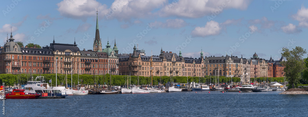 Old sailing and fishing boats at piers at the district Östermalm a sunny day in Stockholm