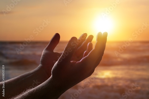 Obraz na płótnie Silhouette human hands open palm up on sunset beach