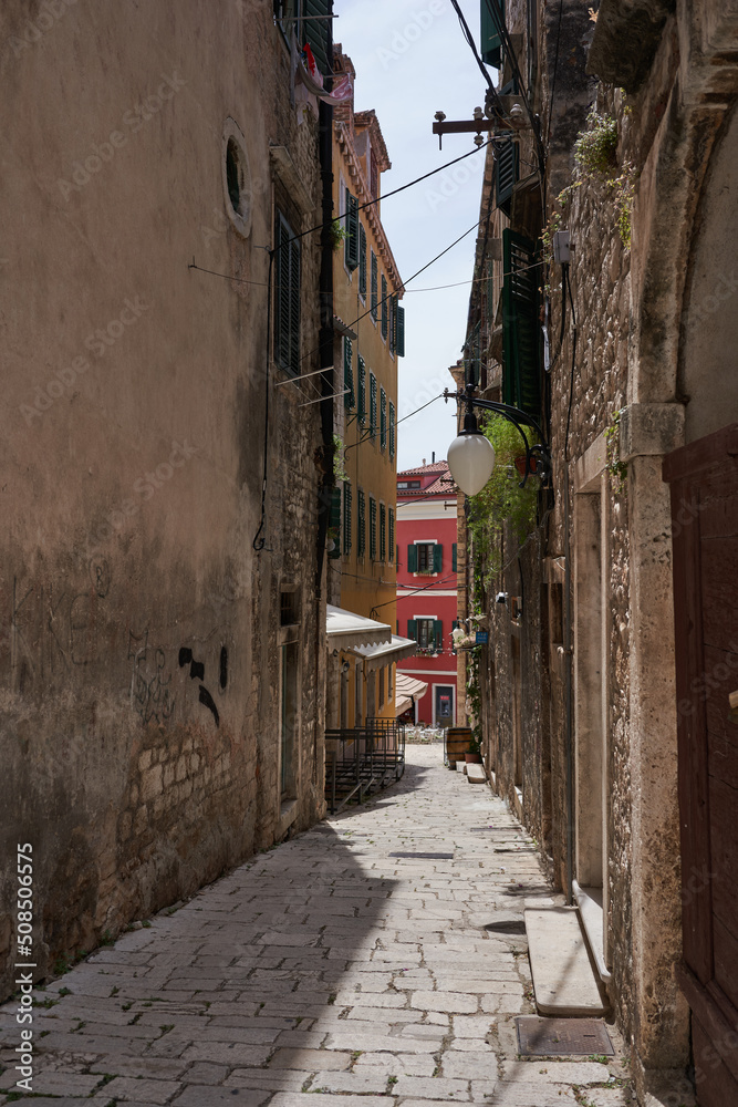 Sibenik, Croatia - May 26, 2022 - narrow old street and yard in Sibenik city, medieval zone