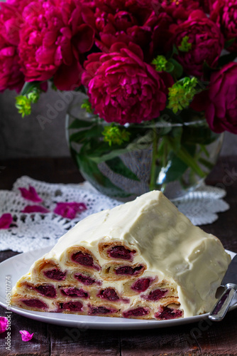 Obraz na płótnie Cake Monastic hut with cherry filling and sour cream, a bouquet of peonies on a wooden table. w salonie
