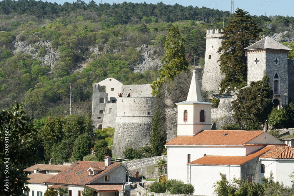 View on Trsat Castle and churh in Rijeka from opposite hill. It lies at the exact spot of an ancient Illyrian and Roman fortress and is surround by tress and buildings.