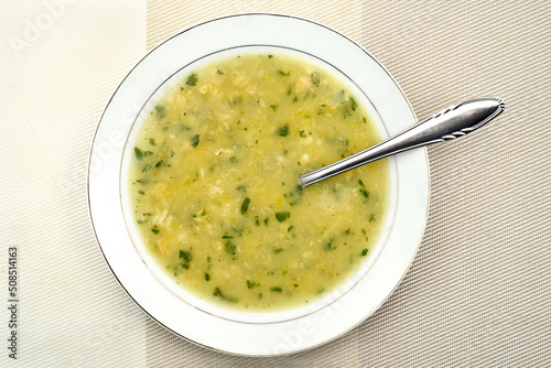 Homemade soup with semolina and egg dumplings with parsley leaves in the white plate. Top view. Healthy diet concept.