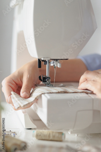 woman sews clothes on a sewing machine in a workshop. work in the production of clothing and textiles. patterns and fabrics for sewing, a woman designer and a sewing tailor sews to order or a
