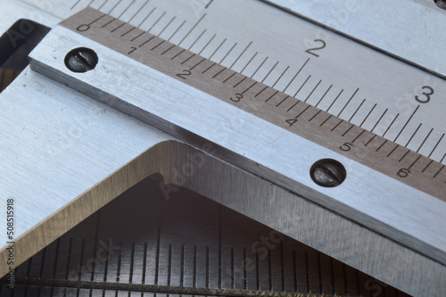 Accurate measuring tool caliper and metal ruler lie on top of each other. close-up.
