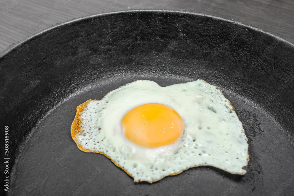 scrambled eggs in a cast iron skillet. Isolated on dark painted wood from above. scrambled eggs in a cast iron skillet. Isolated on dark painted wood from above.