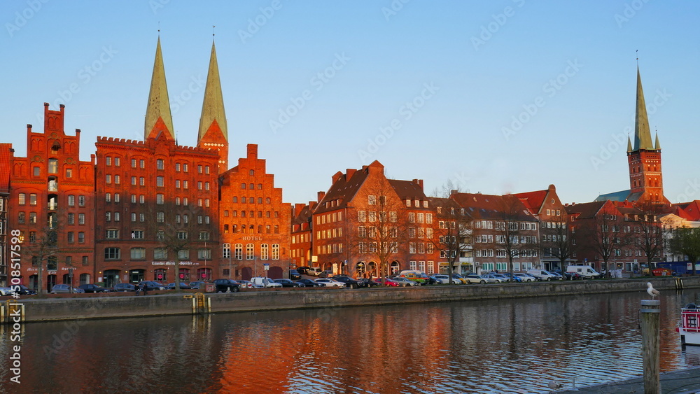 historische Häuserfassaden und Kirchtürme in Lübeck entlang der Trave im Abendlicht